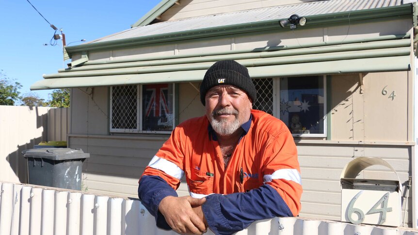 Kalgoorlie resident Tony Anderson wearing orange visibility shirt leaning on his front fence.