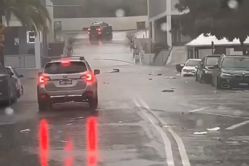 Car with brake lights on as it drives through water on a flooded road