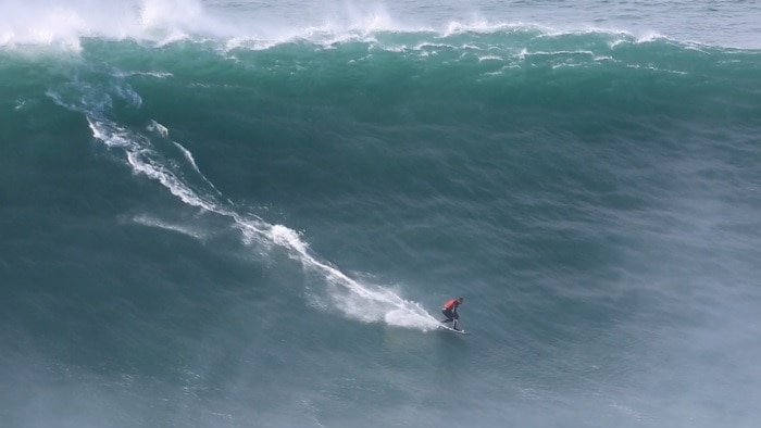 Man riding massive wave on surfboard