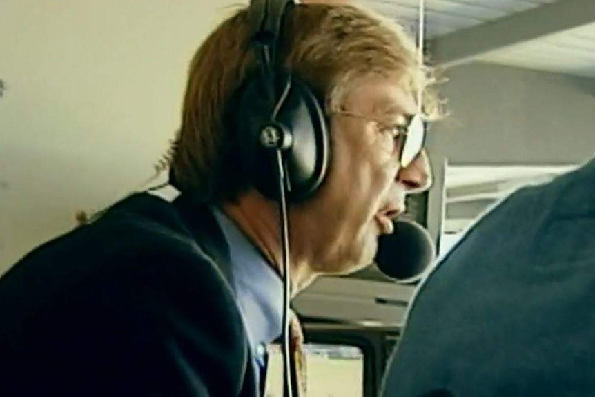 Wearing a headset microphone, Dennis Cometti calls a game.