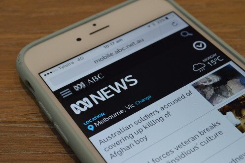 An iPhone screen displays the homepage of the ABC digital website.
