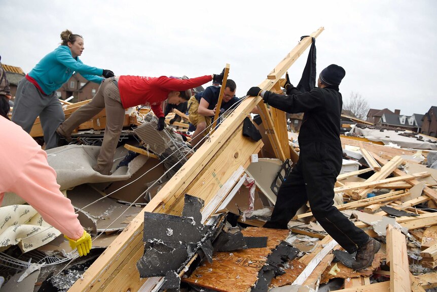 Neighbours help collect clothing and look for pets at a destroyed home.
