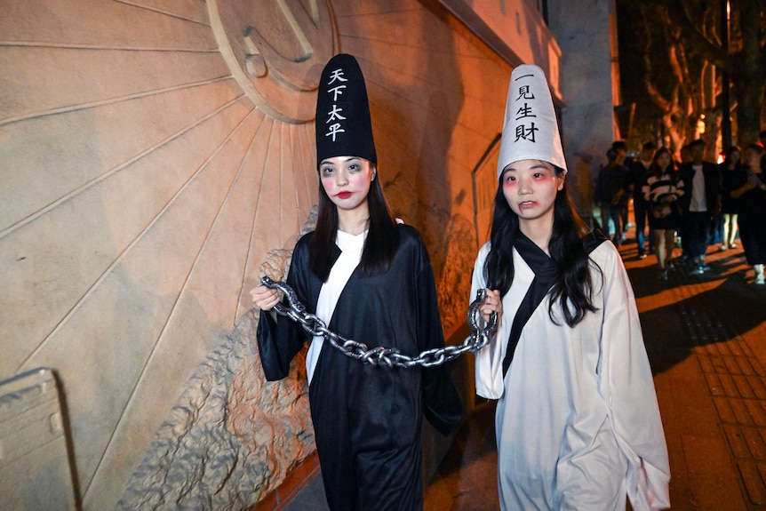 Two girls wearing Halloween costumes.