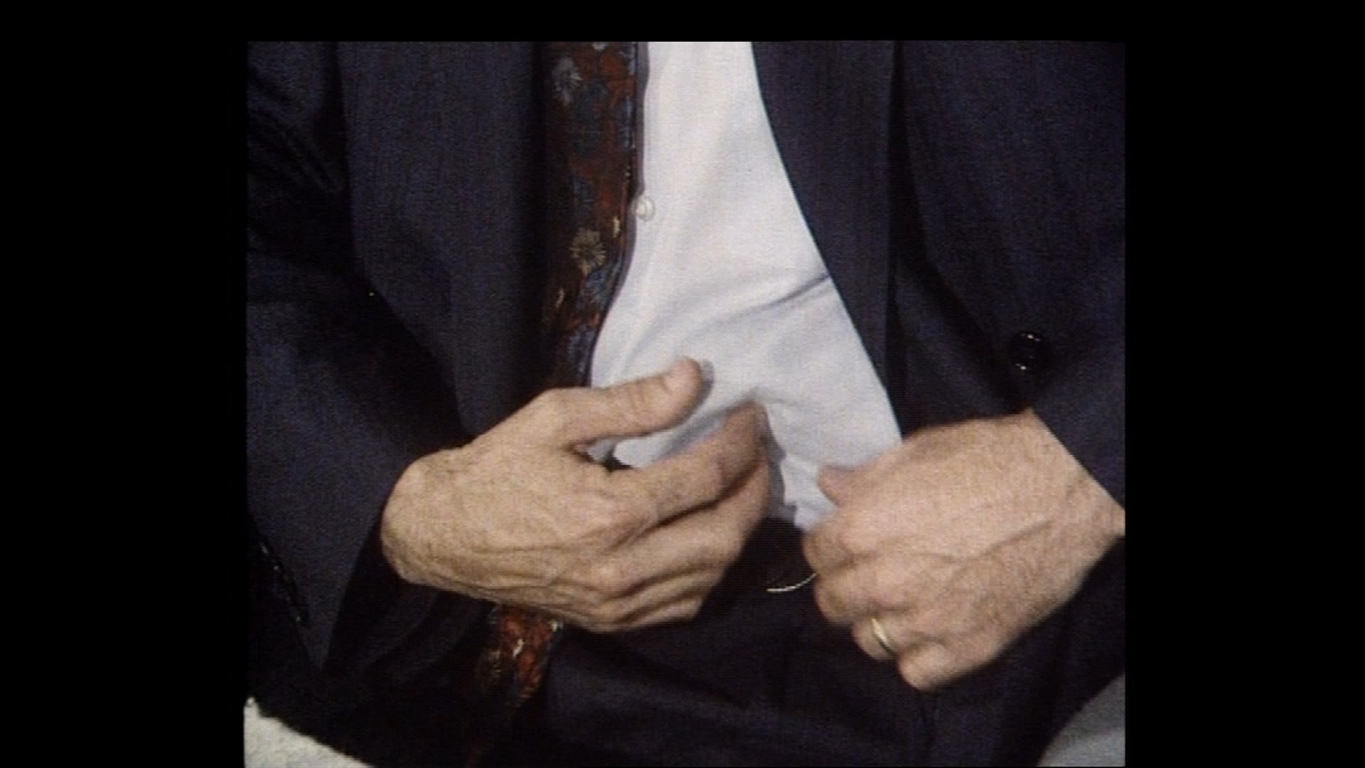 Morecroft's hands maneouvering a lump, Archie, under his tucked in shirt.