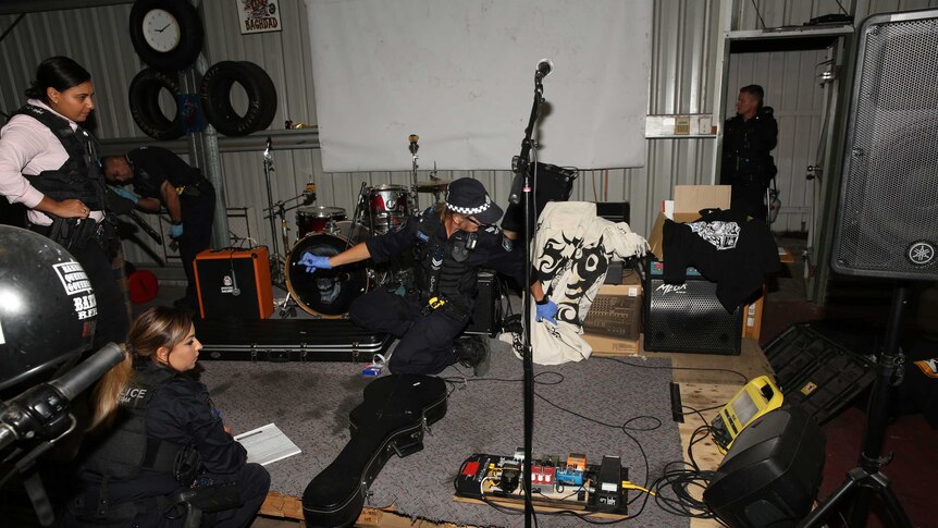 Queensland police officers looking at band equipment in Rebels OMCG club house