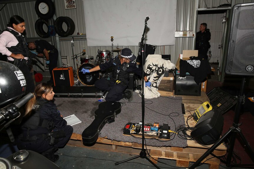 Queensland police officers looking at band equipment in Rebels OMCG club house