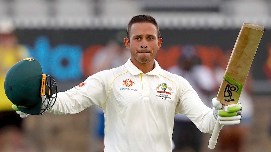 Usman Khawaja raises his bat and helmet as he celebrates his century against Sri Lanka in Canberra