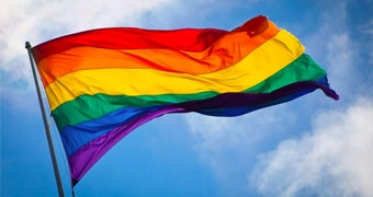 A rainbow flag blows in the wind.