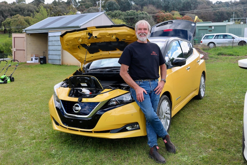 A man leans on a yellow car. 