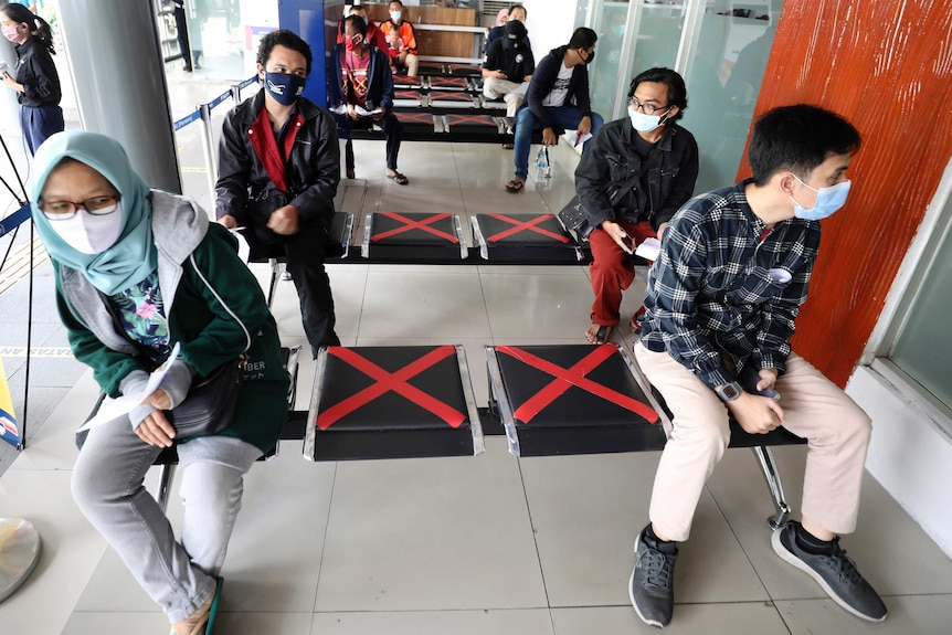 People sit spaced apart as they wait for a coronavirus test required to board long-distance trains.