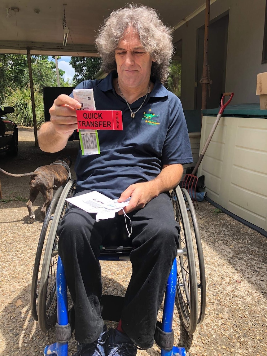 Australian paraplegic athlete Darren Belling looking at his luggage tags