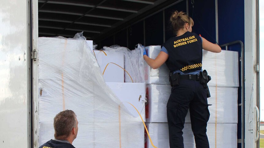 Australian Border Force officers inspect boxes in the back of a truck.