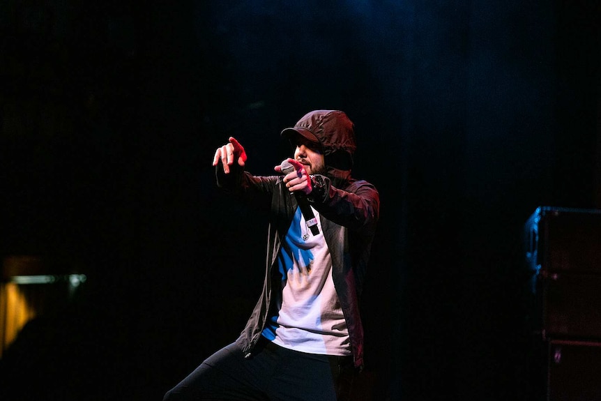 Colour photo of rapper Nooky on stage at Sydney Opera House and pointing with both arms at audience.