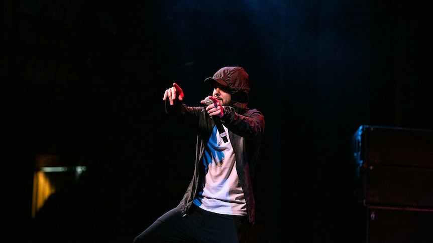 Colour photo of rapper Nooky on stage at Sydney Opera House and pointing with both arms at audience.