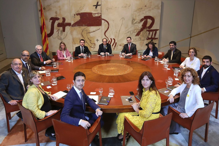 Catalan President Cabinet members are seen sitting around a table facing the camera.