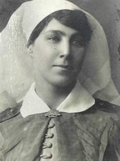 Black and White photo of an Australian nurse with white headpiece and cape clasped at the neck with AIF badge