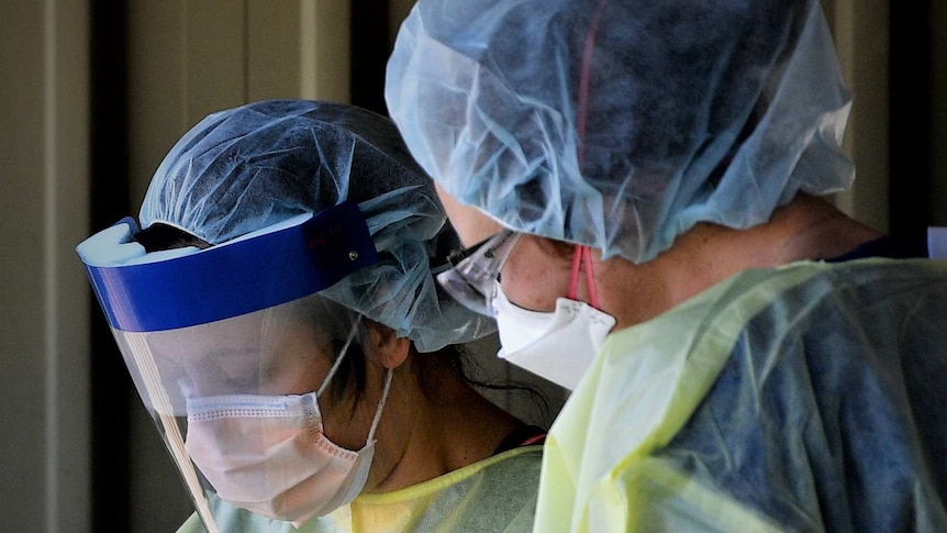 Hospital staff in PPE at a dedicated COVID-19 testing clinic.