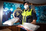 A police officer holds two bags of drugs.