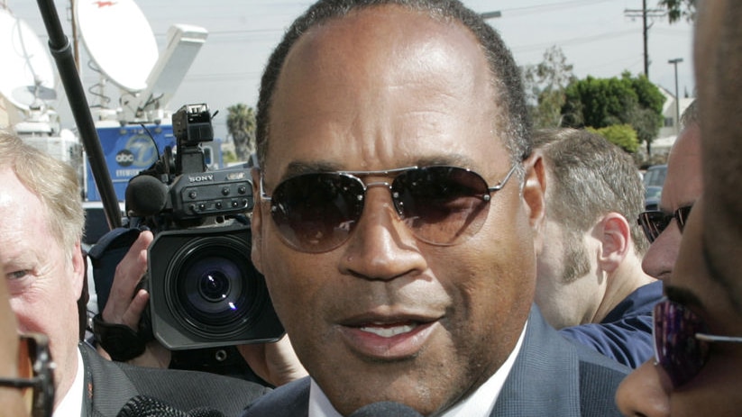 OJ Simpson talks to reporters as he arrives for the funeral of Johnnie Cochran in 2005.
