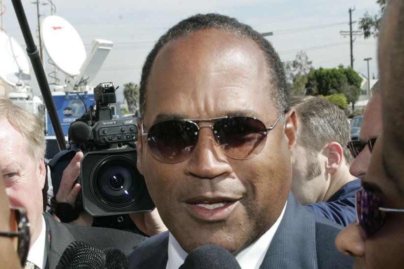 OJ Simpson talks to reporters as he arrives for the funeral of Johnnie Cochran in 2005.