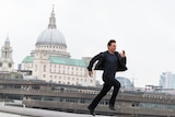 Colour still image of Tom Cruise running on a city rooftop in 2018 film Mission Impossible: Fallout.