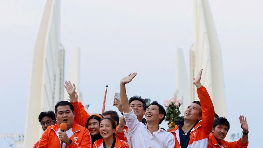 A group of people mainly dressed in orange wave and smile. 