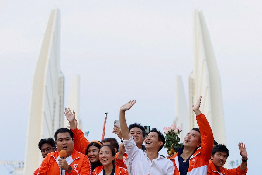 A group of people mainly dressed in orange wave and smile. 