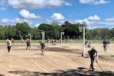 Workers scrub a muddy netball court.