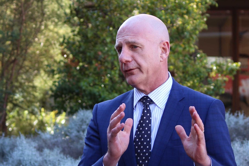 Tasmanian Treasurer Peter Gutwein, wearing a navy suit with white and blue striped shirt and navy tie with white spots.