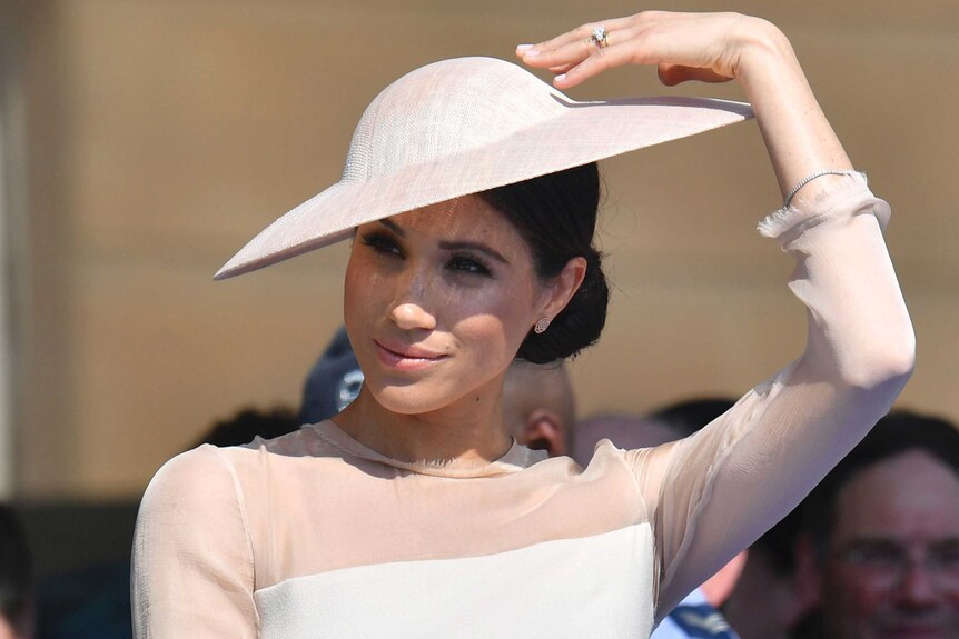 Meghan touches her hat.