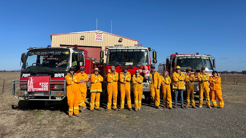 Volunteer firefighters standing together in front of a truck, blue sky.