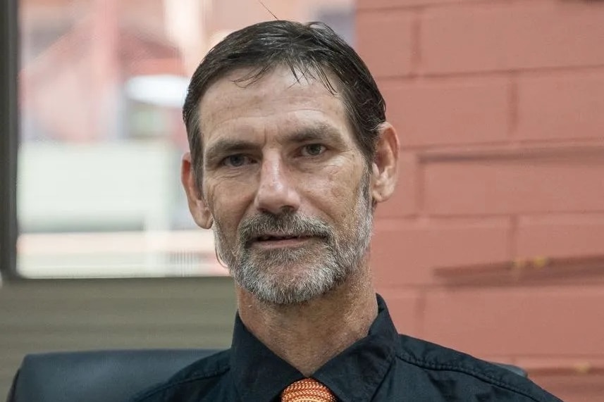 A man in front of a brick wall