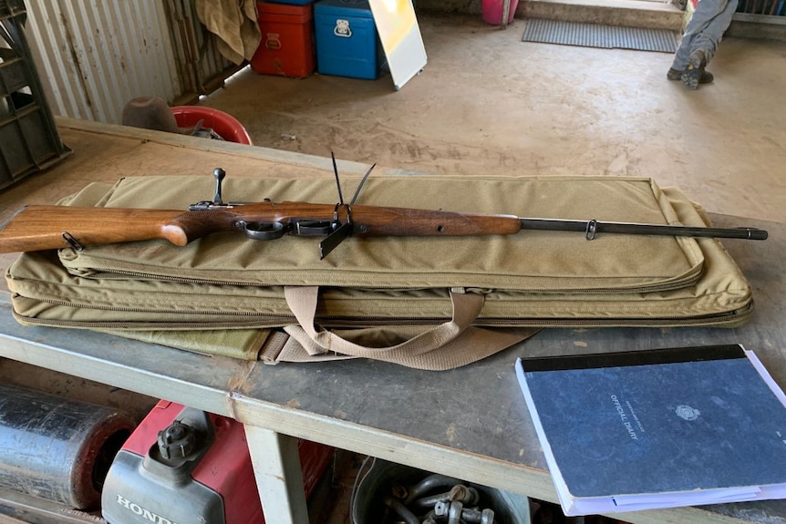 A gun rests on a table beside a police leger.