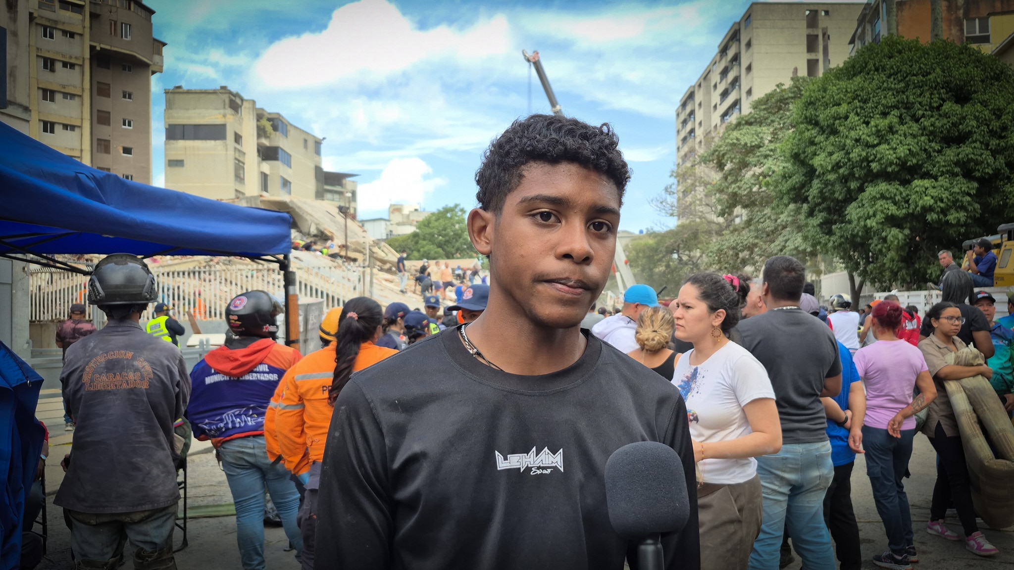 A Venezuelan student wearing a black shirt stands surrounded by others on a street.