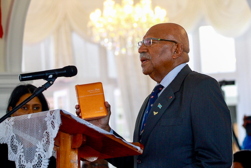 Sitiveni Rabuka holds small bible as he is sworn in as the prime minister of Fiji.