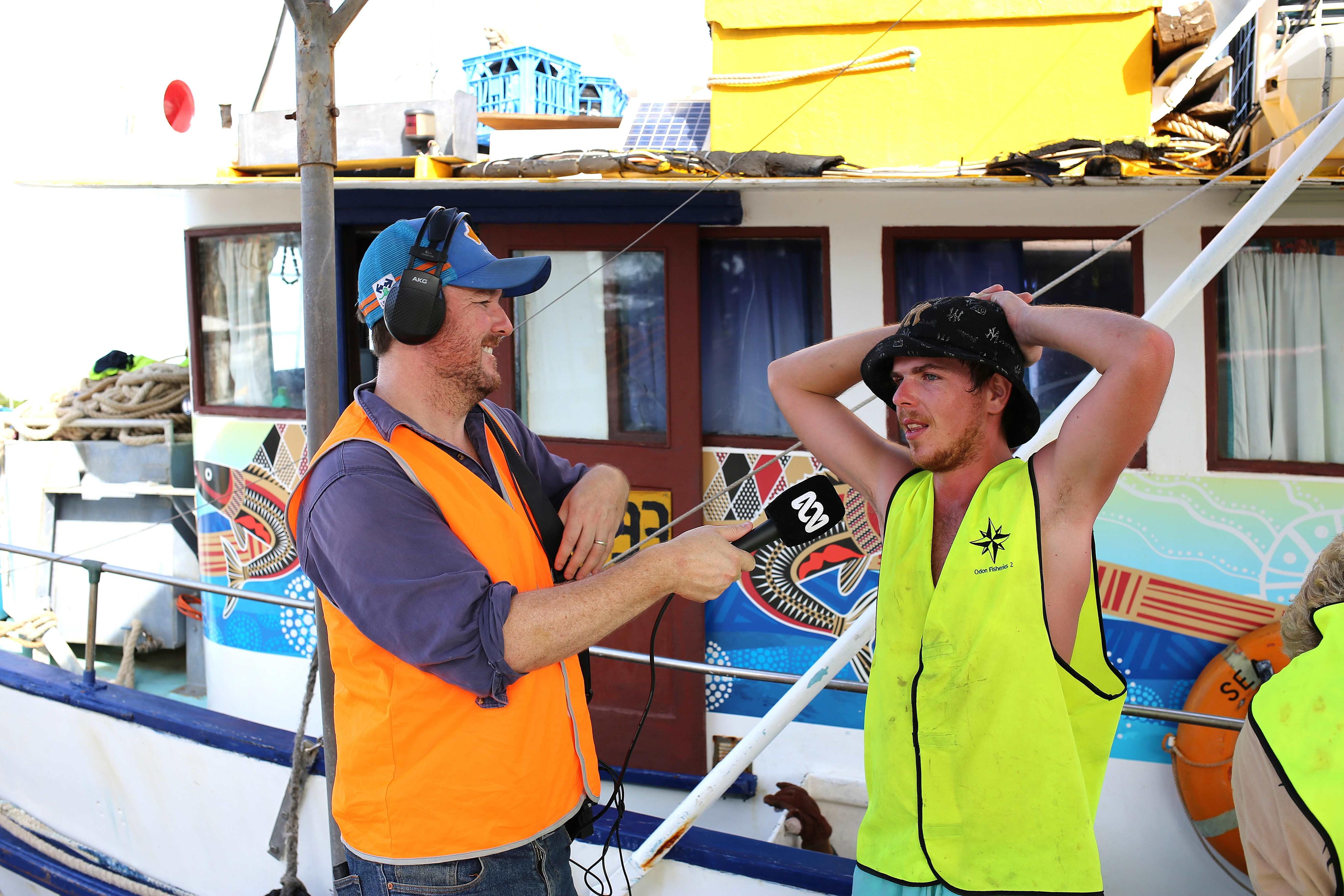Matt Brann interviewing a Spanish mackerel fisherman next to a boat