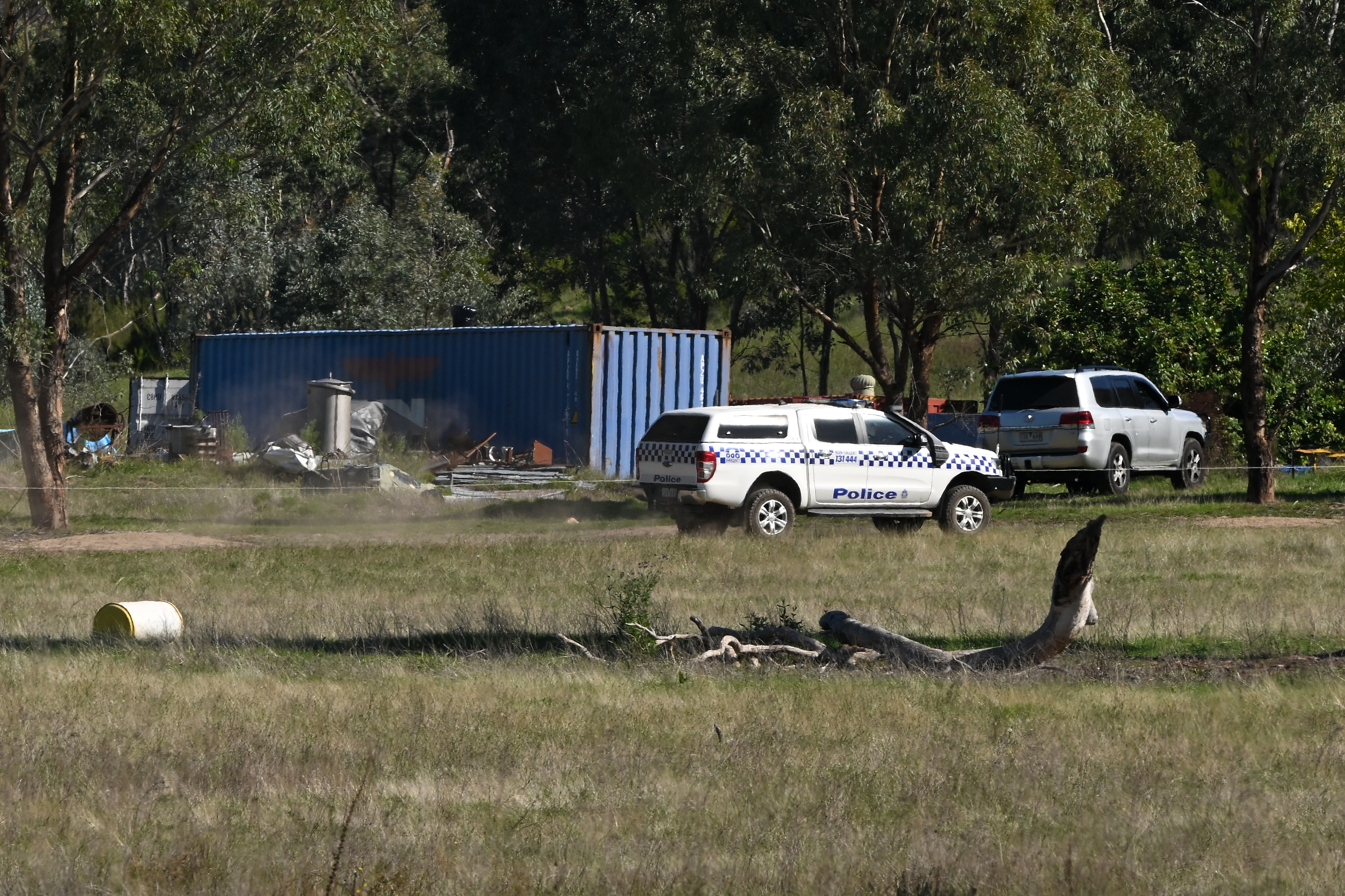 A shipping container and police cars on the property where Dezi Freeman was found