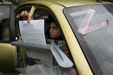 A woman places a ballot paper into a box from her car window.