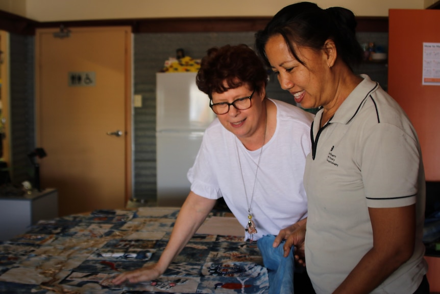 Two women look at blocks for a quilt project.