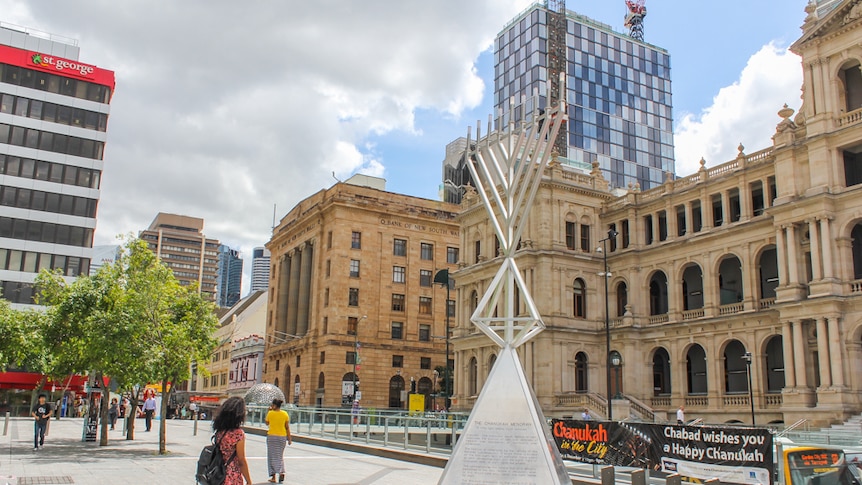 People stop to read about the large menorah standing in the Brisbane CBD.