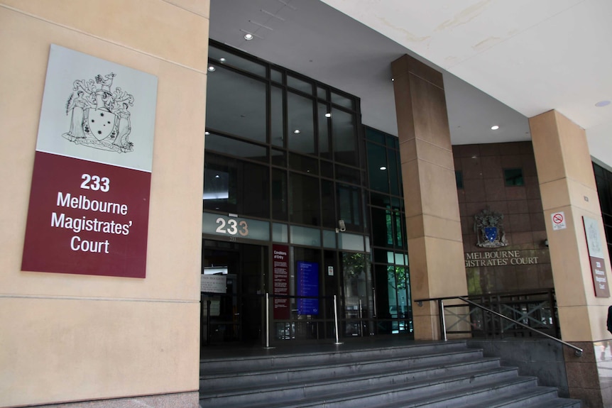 The front doors of the Melbourne Magistrates' Court with a sign to the right of the door.