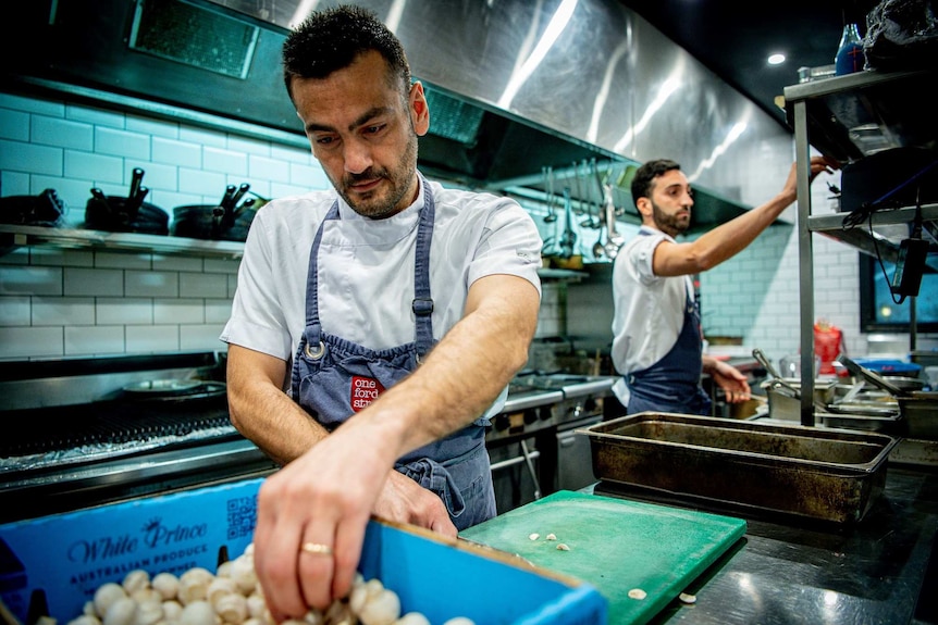 Two chefs work in a restaurant kitchen.