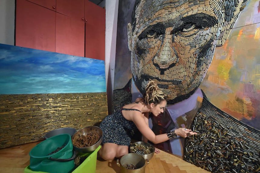 Ukrainian artist Daria Marchenko works on a portrait of Russian President Vladimir Putin