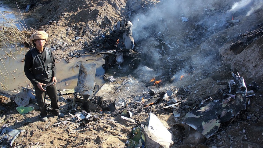 IS fighter stands beside smoking wreckage