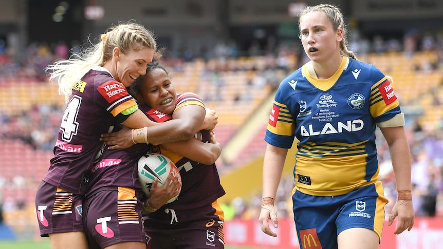 Three Brisbane Broncos NRLW players embrace as they celebrate a try against Parramatta.