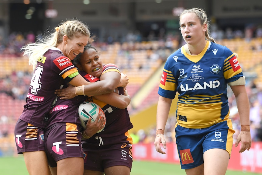 Three Brisbane Broncos NRLW players embrace as they celebrate a try against Parramatta.