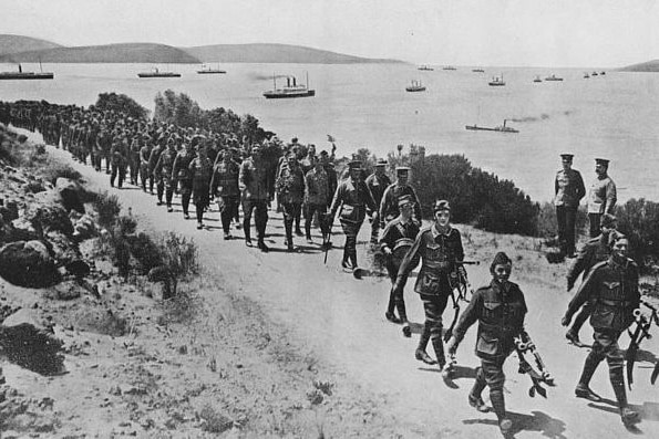 A historic photo of troops marching on the edge of a bay.
