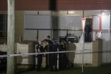 Police stand at night at home where a man and woman were found dead in Albany Creek