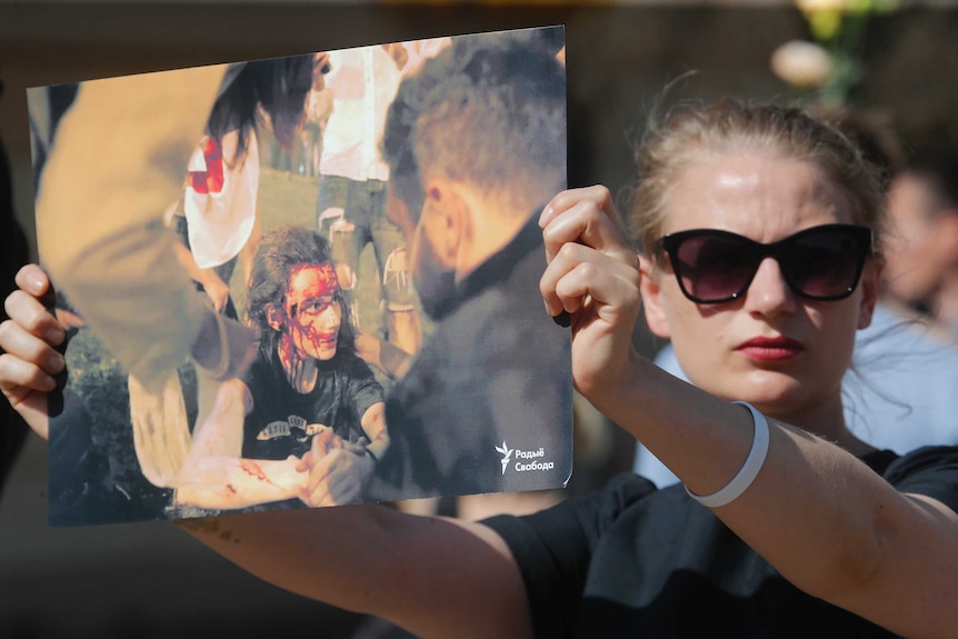 A woman holds a photo of a protester, beaten by police during a rally in Minsk.