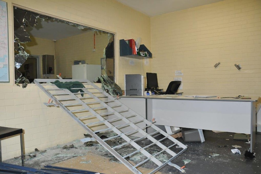 A large window smashed in a staff area of Greenough regional prison with a large metal frame lying below it.